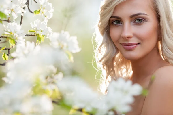 Blonde woman in a flowered garden — Stock Photo, Image