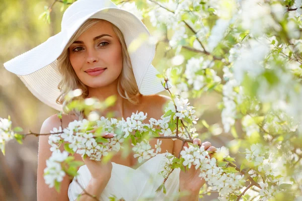 Blond kvinna i en blomstrande trädgård — Stockfoto
