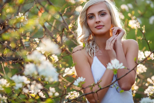 Blond kvinna i en blomstrande trädgård — Stockfoto