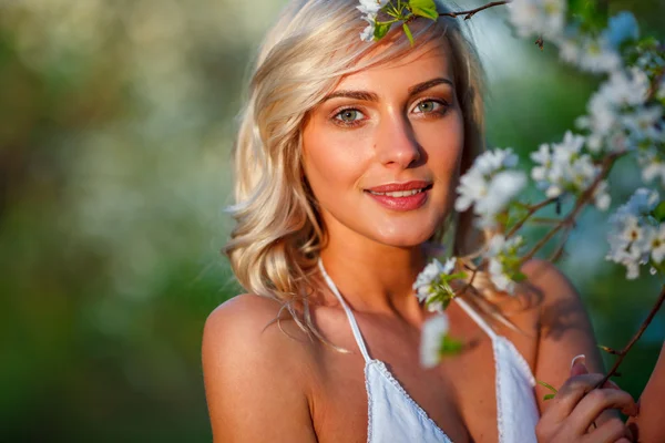 Blond kvinna i en blomstrande trädgård — Stockfoto