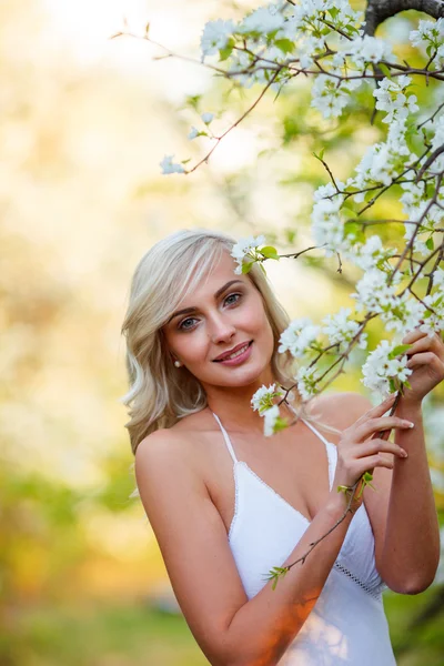 Blonde woman in a flowered garden — Stock Photo, Image