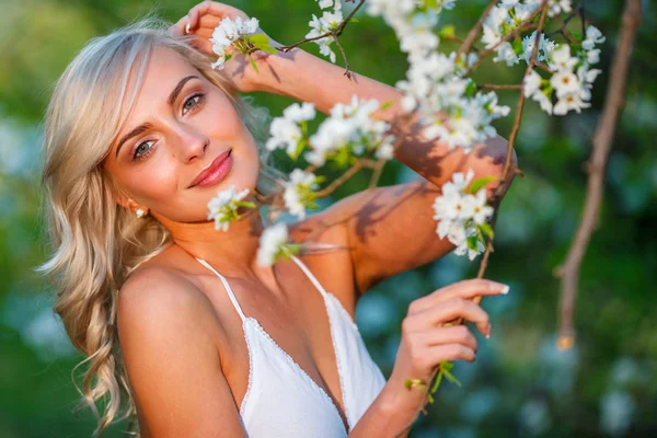 Blonde woman in a flowered garden — Stock Photo, Image