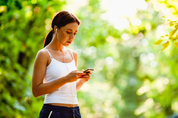 Kvinna med audio spelaren gör fitness i stadsparken — Stockfoto