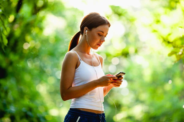 Kobieta z odtwarzacza robi fitness w parku miejskim — Zdjęcie stockowe