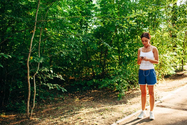 Mujer con reproductor de audio haciendo fitness en el parque de la ciudad —  Fotos de Stock