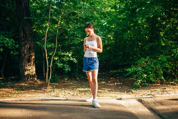 Mulher com leitor de áudio fazendo fitness no parque da cidade — Fotografia de Stock