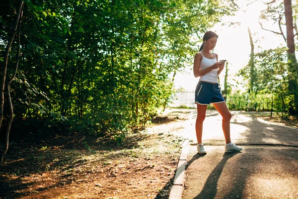 Mulher com leitor de áudio fazendo fitness no parque da cidade — Fotografia de Stock