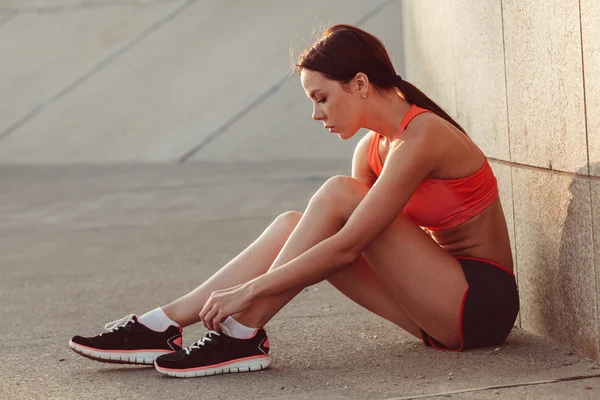 Runner kvinne sitter på bakken og slips lisser – stockfoto