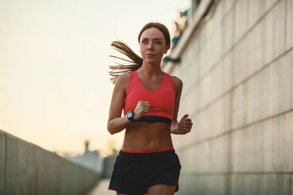 Donna che corre lungo un muro di cemento — Foto Stock