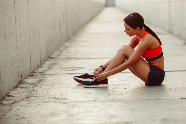 Mujer corredora sentada en el suelo y corbata cordones — Foto de Stock