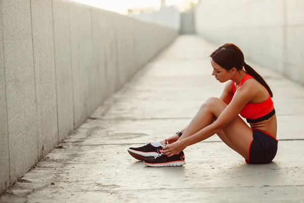 Coureur femme assis sur le sol et lacets cravate — Photo