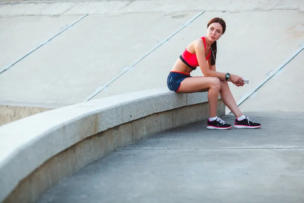 Сидящая усталая спортивная женщина — стоковое фото