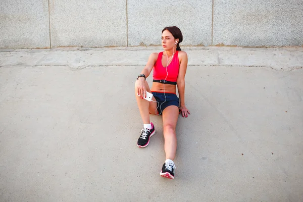 Sitting runner woman listening music — Stock Photo, Image