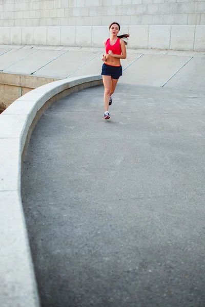 Woman runnning along granite curved parapet — Stock Photo, Image