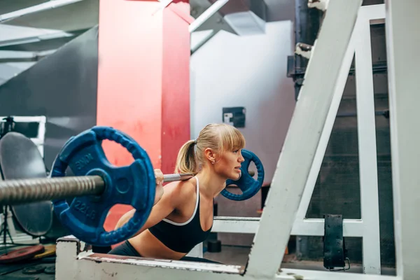 Fitness žena dělá činka dřepy v tělocvičně — Stock fotografie