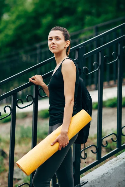 Mujer con una esterilla de yoga al aire libre —  Fotos de Stock