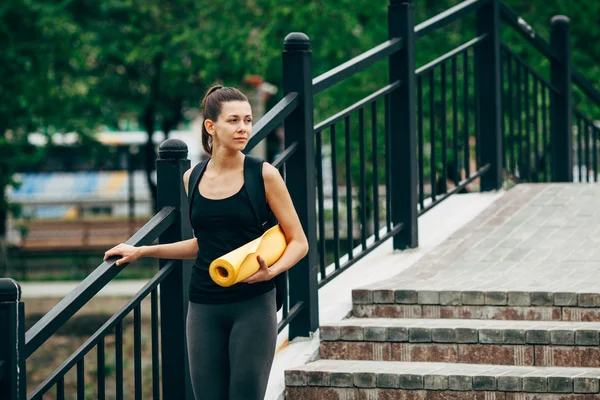 Mujer con una esterilla de yoga al aire libre —  Fotos de Stock