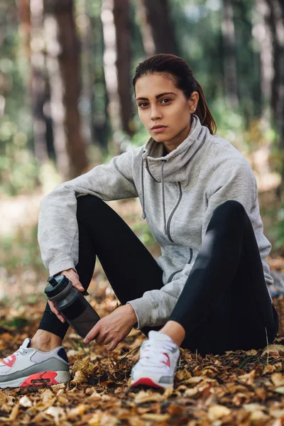 Runner woman rest on the leaves in park — Stok Foto