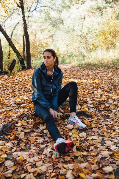 Runner woman rest on the leaves in park — Stock Photo, Image