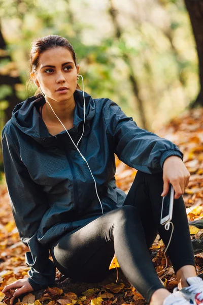 Runner woman rest on the leaves in park — Stock Photo, Image