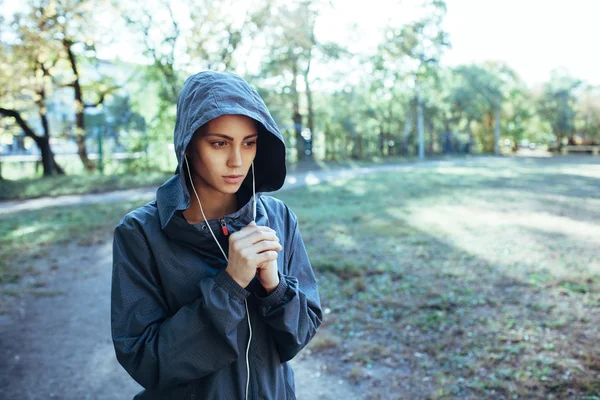 Mujer deportiva con capucha chaqueta y escuchar música —  Fotos de Stock