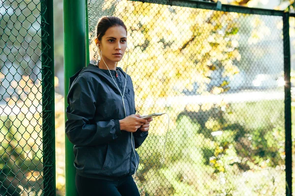 Mujer deportiva con capucha chaqueta y escuchar música —  Fotos de Stock