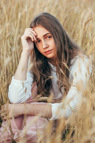 Giovane donna vestita seduta in campo con grano — Foto Stock