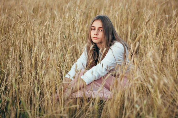 Dragen jurk jonge vrouw zitten in veld met tarwe — Stockfoto