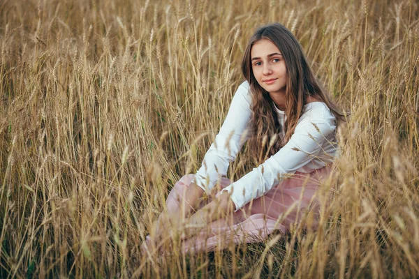 Buğday alanı oturan genç kadın giyiyor elbise — Stok fotoğraf