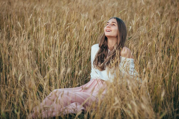 Mujer joven con vestido sentado en el campo con trigo — Foto de Stock