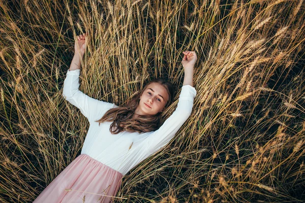 Mujer joven con vestido acostado en el campo con trigo — Foto de Stock