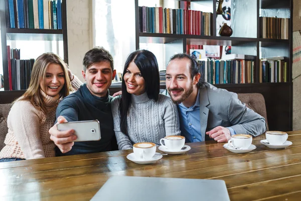 Groep vrienden met koffie en kijken naar smartphone — Stockfoto