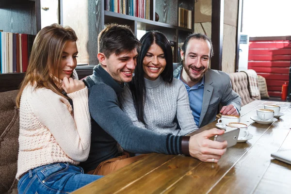 Groep vrienden met koffie en kijken naar smartphone — Stockfoto