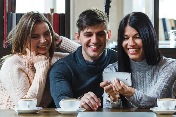 Groep vrienden met koffie en kijken naar smartphone — Stockfoto