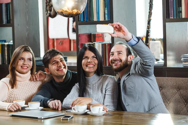 Groep vrienden met koffie en kijken naar smartphone — Stockfoto