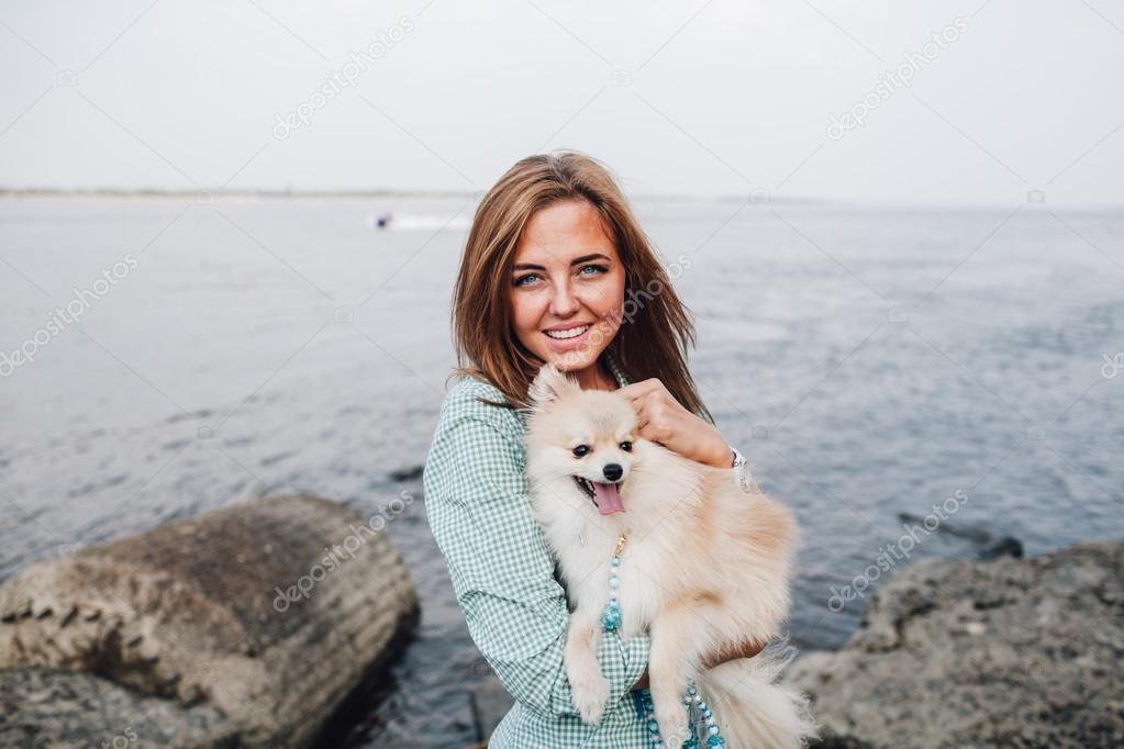 Young woman is holding dog outdoors