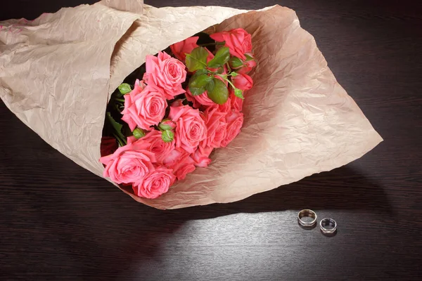 Ramo Rosas Paquete Papel Arrugado Anillos Boda Una Mesa Oscura Imagen de stock