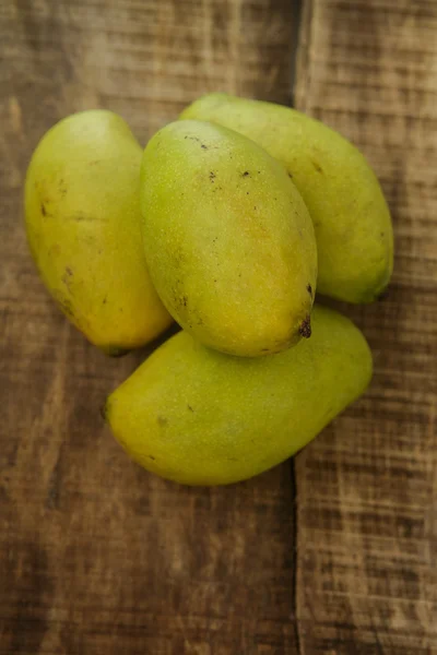 Vista superior de quatro Mangos na tabela de madeira — Fotografia de Stock