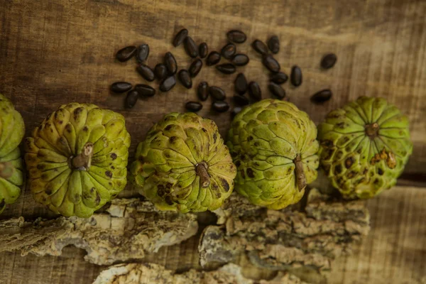 Ripe Sugar-apple Seeds by Unbroken Fruits on Wooden Table