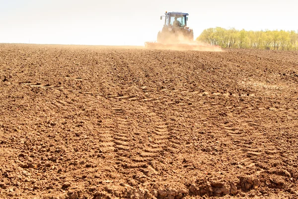 Távoli traktor levelek friss dal nedves felszántott mező — Stock Fotó