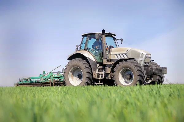 Traktor fährt auf Horizontlinie grüne Wiese im Vordergrund — Stockfoto