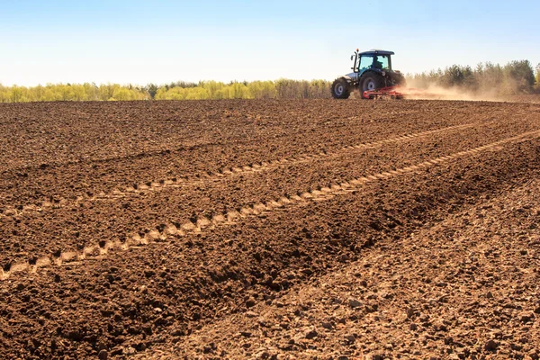 Grubber arbeitet auf gepflügtem Feld macht Staub — Stockfoto