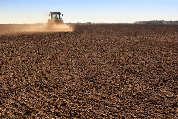 Cultivador opera en campo arado hace polvo Imagen De Stock