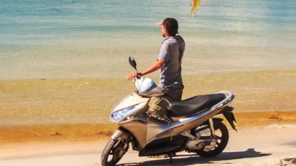 Людина з скутером на пляжі — стокове відео
