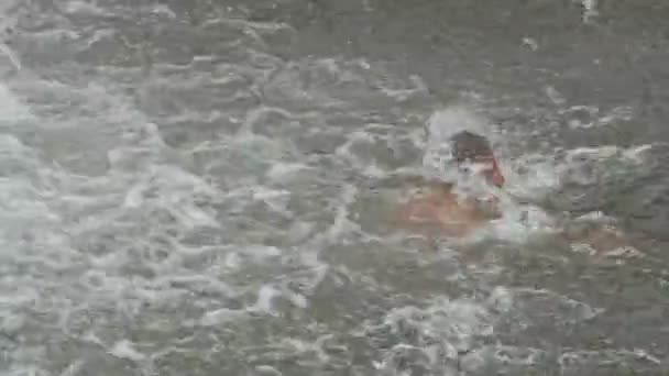 Mann schwimmt Glücksspiel unter schäumendem Wasserfall — Stockvideo