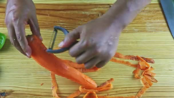 Vue de dessus sur les mains de l'homme pelant grande carotte orange mûre par couteau spécial — Video