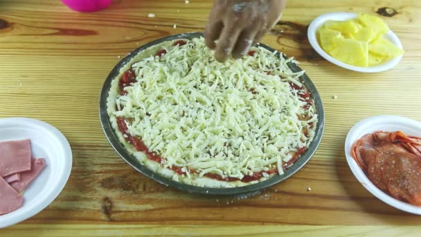 Top view närbild på man händer sätta riven hårdost på pizza med tomatsås — Stockvideo