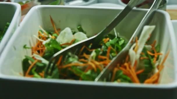Enfoque de primer plano en un tazón blanco profundo con zanahoria rallada y hojas de ensalada mixtas — Vídeos de Stock