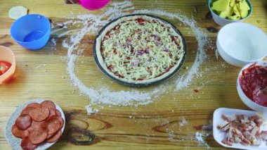 Erkek ellerine üstten bakıldığında yarım kalmış soslu ve peynirli pizzaya soğan parçaları konur.