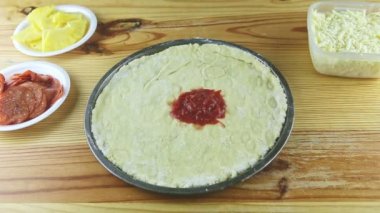 Üst manzara yuvarlak pizza hamurundan uzaklaşır ve ahşap masada yağ damlaları olur.